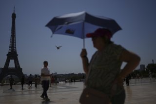 Un touriste s'abrite du soleil avec une ombrelle, sur le Trocadero à Paris, lors d'un épisode caniculaire de juillet. (image d'illustration) KEYSTONE/AP/CHRISTOPHE ENA